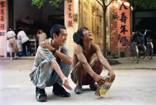 《我和我的老師》鄭國谷(1970-)攝影/錄像/行為 182 × 270 cm 1993 年
1993年,23歲的鄭國谷以《我和我的老師》徹底拋卻過去,登上了他20余年如一日的年輕藝術之途,至今仍不見盡頭。“我的老師”是鄭國谷在家鄉陽江街上偶然遇見的一位瘋子,一無所有,卻無比自由。鄭國谷讀到他不按常理出牌的衣食住行方式背后的顛覆性提問,他說自己雖然蹲下來和“我的老師”一起大笑,但還是“沒他放得開,略顯拘謹”。然而,非常規能量已經接續,鄭國谷之后20年如一日的持續性“無法不破,不立一法”的藝術實踐不斷積淀著作品的厚度:他是最早一批進行實驗攝影的藝術家之一,那些由傻瓜相機拍攝的《度蜜月》的作品被很多藝術家所深深銘記;2001年,他購買了七套頂層商品房,打通連接建成自己的家,在房地產市場崛起之前已經在發問;他推動成立的陽江組致力于對傳統書法破綻的尋找,并關注到向來被忽視的底層書寫;他按照先鋒藝術家的生活方式將教學帶到酒吧,給每位學生打99分;他建于郊區的3萬平米個人當代藝術實驗田則經歷了從天馬行空、漫無邊界的“帝國”到“了園”的不同階段,耗近十年之功而至今未了,土地制度、人權、資本、想象力、藝術的邊界等等均攪和在一起……很少有藝術家像鄭國谷那樣將自己的生活和藝術的先鋒實驗像如此緊密而多樣地交織在一起。這位受到多方重視的藝術家既是海內外的重要大展的常客,卻又始終沒有離開自己出生的小城陽江,吃酒喝茶關照家人,并把身邊的生活重又變成藝術。
《我和我的老師》鄭國谷(1970-)攝影/錄像/行為 182 × 270 cm 1993 年
1993年,23歲的鄭國谷以《我和我的老師》徹底拋卻過去,登上了他20余年如一日的年輕藝術之途,至今仍不見盡頭。“我的老師”是鄭國谷在家鄉陽江街上偶然遇見的一位瘋子,一無所有,卻無比自由。鄭國谷讀到他不按常理出牌的衣食住行方式背后的顛覆性提問,他說自己雖然蹲下來和“我的老師”一起大笑,但還是“沒他放得開,略顯拘謹”。然而,非常規能量已經接續,鄭國谷之后20年如一日的持續性“無法不破,不立一法”的藝術實踐不斷積淀著作品的厚度:他是最早一批進行實驗攝影的藝術家之一,那些由傻瓜相機拍攝的《度蜜月》的作品被很多藝術家所深深銘記;2001年,他購買了七套頂層商品房,打通連接建成自己的家,在房地產市場崛起之前已經在發問;他推動成立的陽江組致力于對傳統書法破綻的尋找,并關注到向來被忽視的底層書寫;他按照先鋒藝術家的生活方式將教學帶到酒吧,給每位學生打99分;他建于郊區的3萬平米個人當代藝術實驗田則經歷了從天馬行空、漫無邊界的“帝國”到“了園”的不同階段,耗近十年之功而至今未了,土地制度、人權、資本、想象力、藝術的邊界等等均攪和在一起……很少有藝術家像鄭國谷那樣將自己的生活和藝術的先鋒實驗像如此緊密而多樣地交織在一起。這位受到多方重視的藝術家既是海內外的重要大展的常客,卻又始終沒有離開自己出生的小城陽江,吃酒喝茶關照家人,并把身邊的生活重又變成藝術。